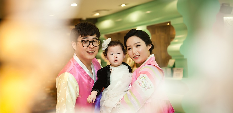 3인 가족 정면, 아기는 카메라를 응시하고 부모는 미소