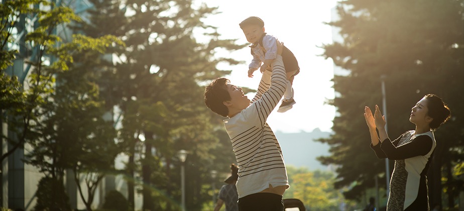 역광 속 아빠가 아기를 들어올리는 3인 가족 야외 스냅