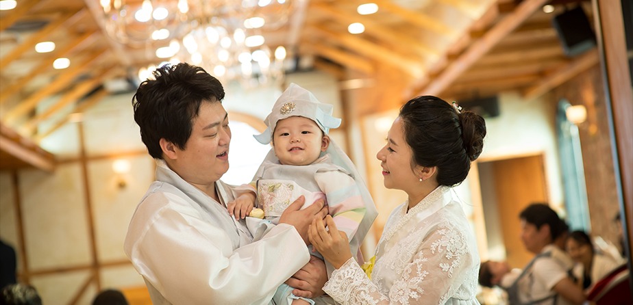 돌잔치홀 실내에서 한복 차림 부모와 아기 가족 스냅