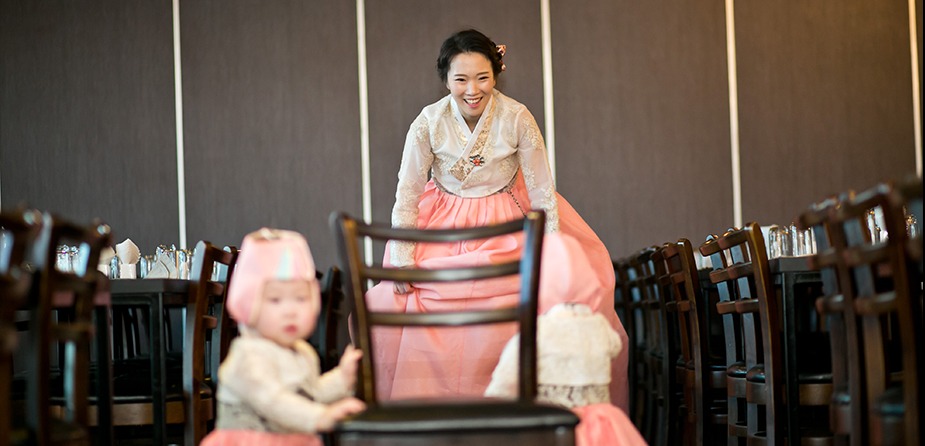 홀 의자 사이 쌍둥이 앞, 뒤에서 웃으며 오는 엄마